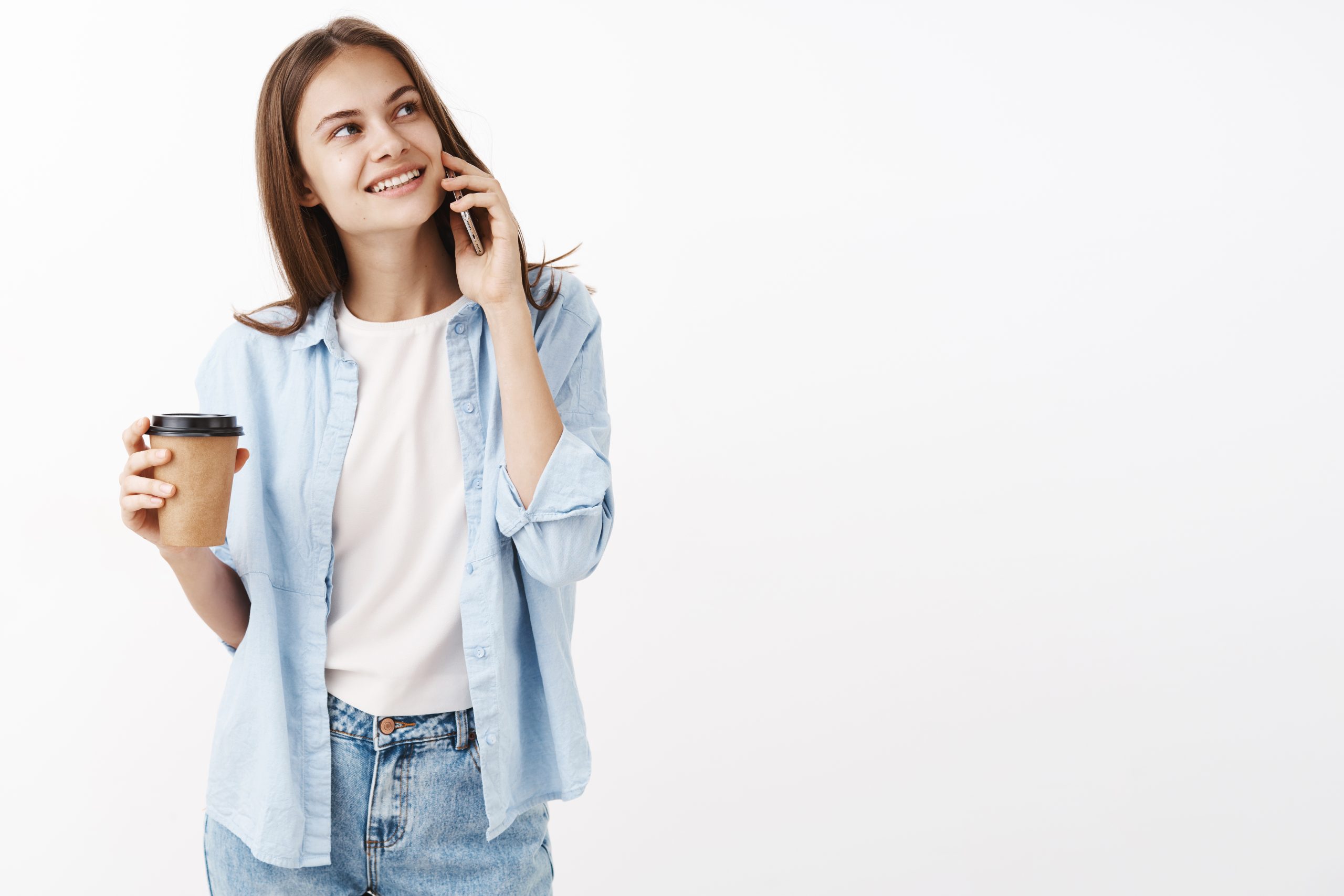cute happy woman take drink cafe near office holding smartphone near ear gazing dreamy carefree upper right corner grinning while standing with paper cup coffee hand scaled