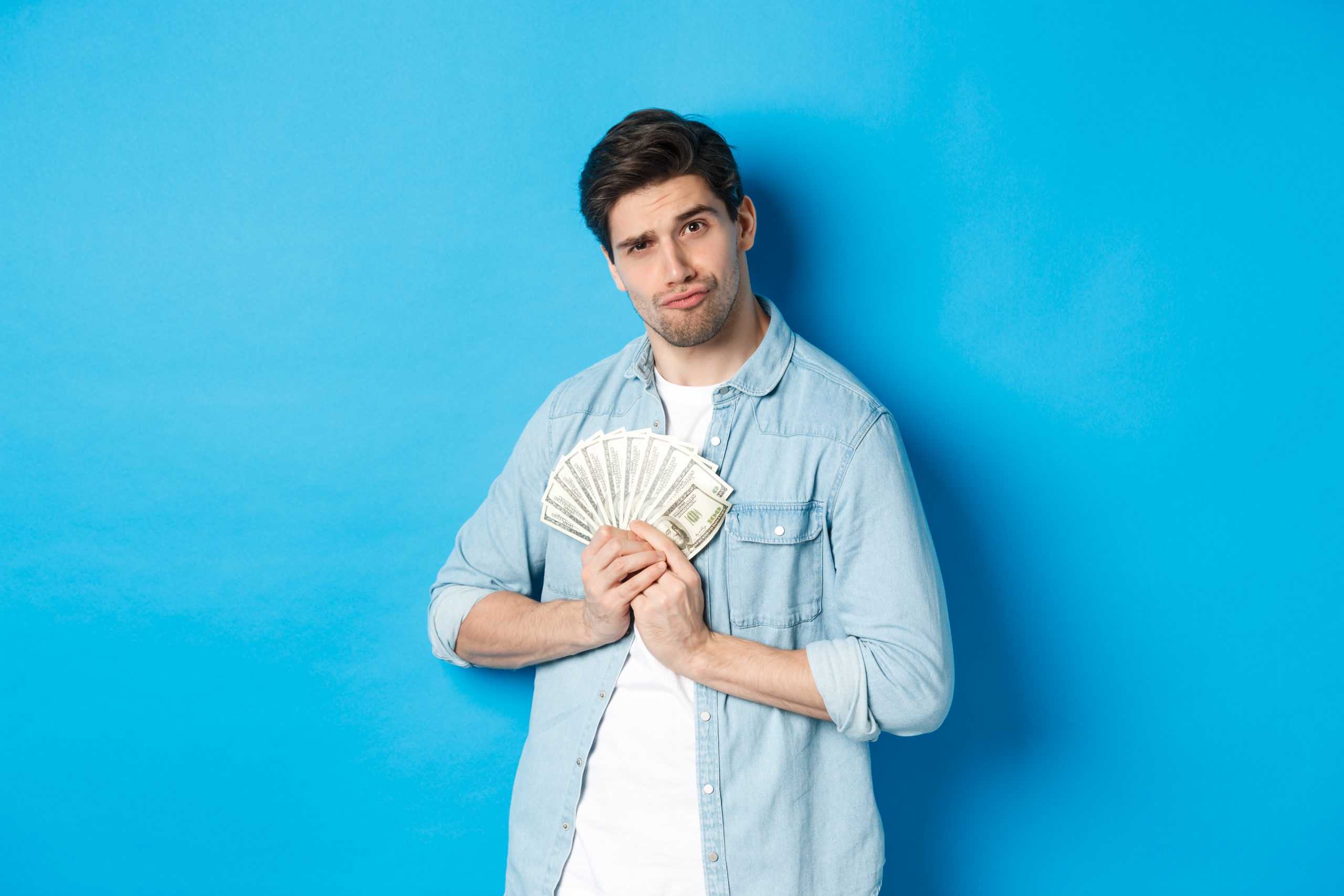 handsome young man keeping money himself smiling looking greedy standing blue background scaled