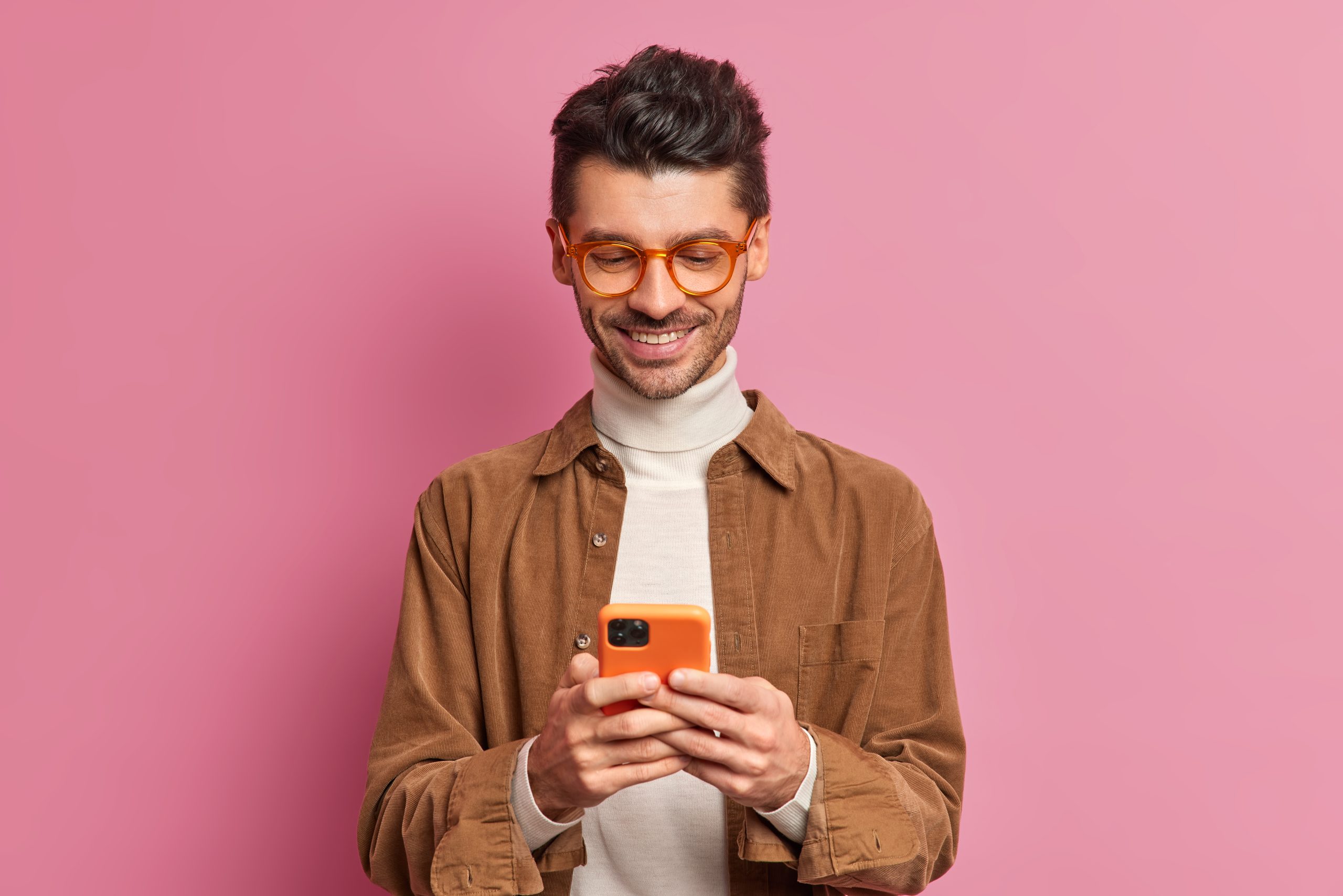 studio shot european man blogger types text messages smartphone smiles pleasantly scaled
